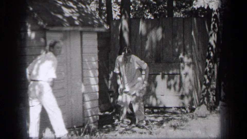 In the Cleveland yard scene, one man in light clothing faces a man in work clothes standing beside the wooden shed.