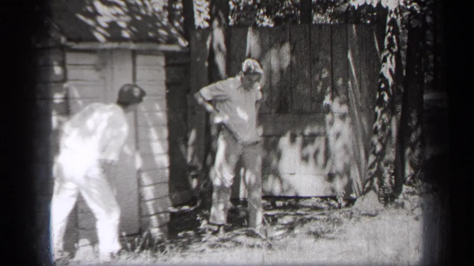 Near the end of the clip, one man bends forward while another stands by the shed in the Cleveland backyard footage.