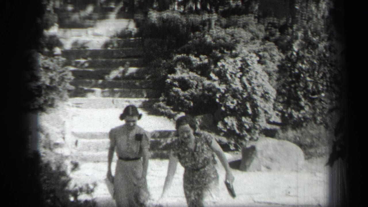 Two women descend outdoor steps beside dense shrubs and rocks.