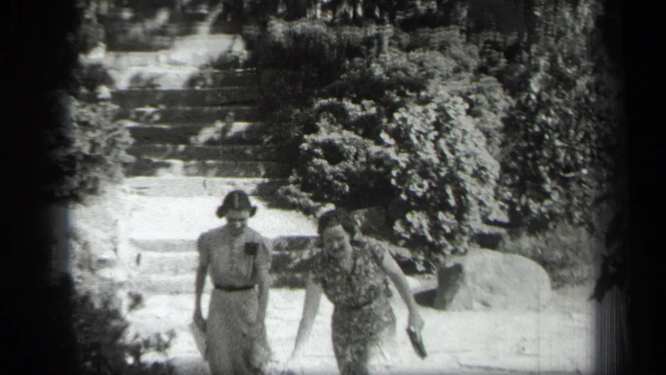 Two women in 1930s attire walk down a stone garden stairway in the Cleveland home-movie scene.