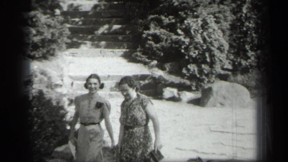 In the 1938 Cleveland footage, two women approach the camera from the stone stairway and garden path.