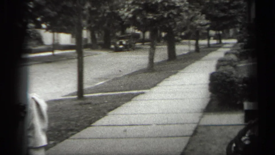 The camera lingers on the Cleveland sidewalk and street after the women have mostly exited, with trees, lawns, and a distant car visible.