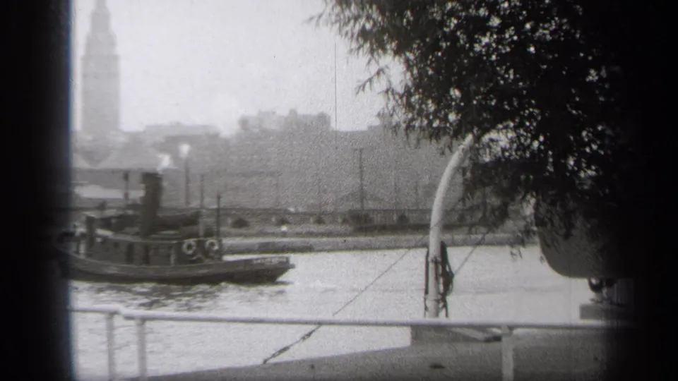 The Cleveland tugboat has moved toward the left edge, leaving more open river and dockside railing visible beneath a hazy 1938 waterfront background.
