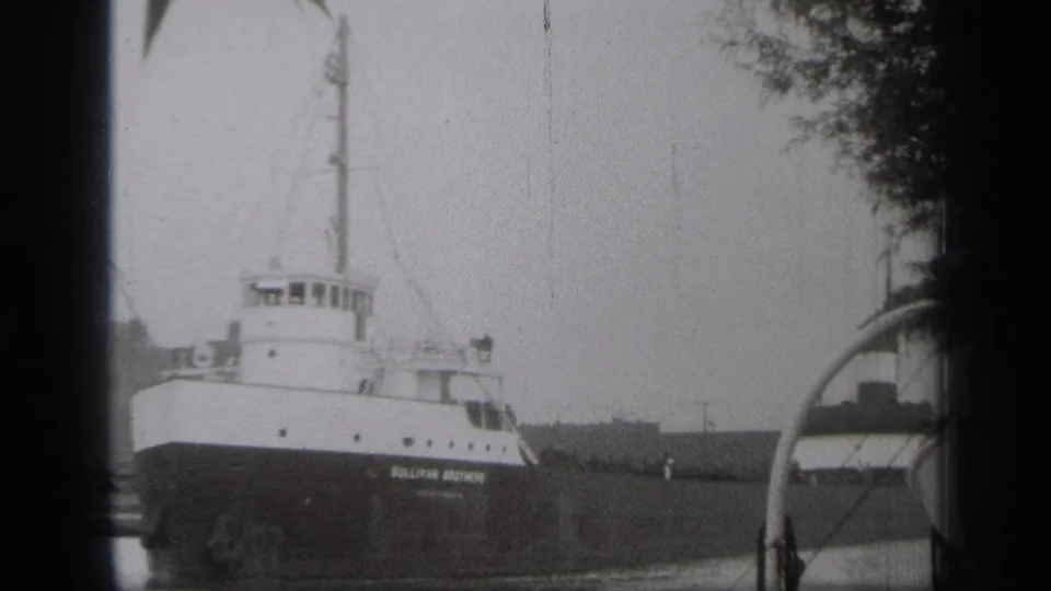 The SULLIVAN BROTHERS name is visible on the freighter hull as it moves past the Cleveland waterfront.