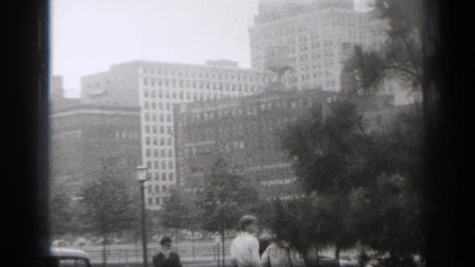 Black-and-white 1938 Cleveland street view with downtown buildings, trees, pedestrians, and a car visible near the lower frame.