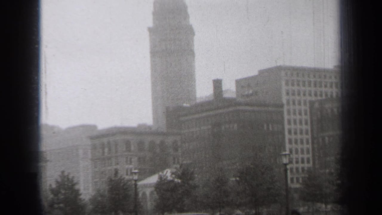 Foggy downtown view with a tall tower rising behind lower buildings and trees.