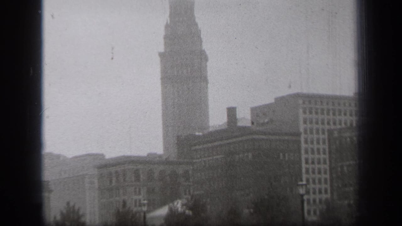 Tall tower and nearby office buildings seen through haze with film gate edges.