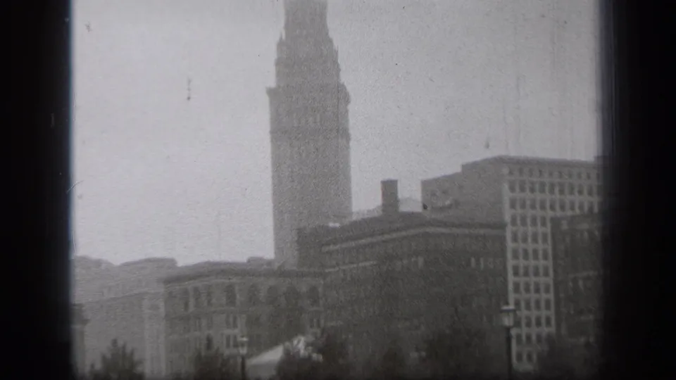 Fog-softened 1938 Cleveland cityscape showing a tall tower, masonry buildings, and a grid-window high-rise.