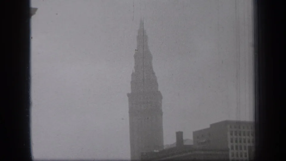 Final 1938 Cleveland frame showing the tower against a pale foggy sky with adjacent downtown buildings below.