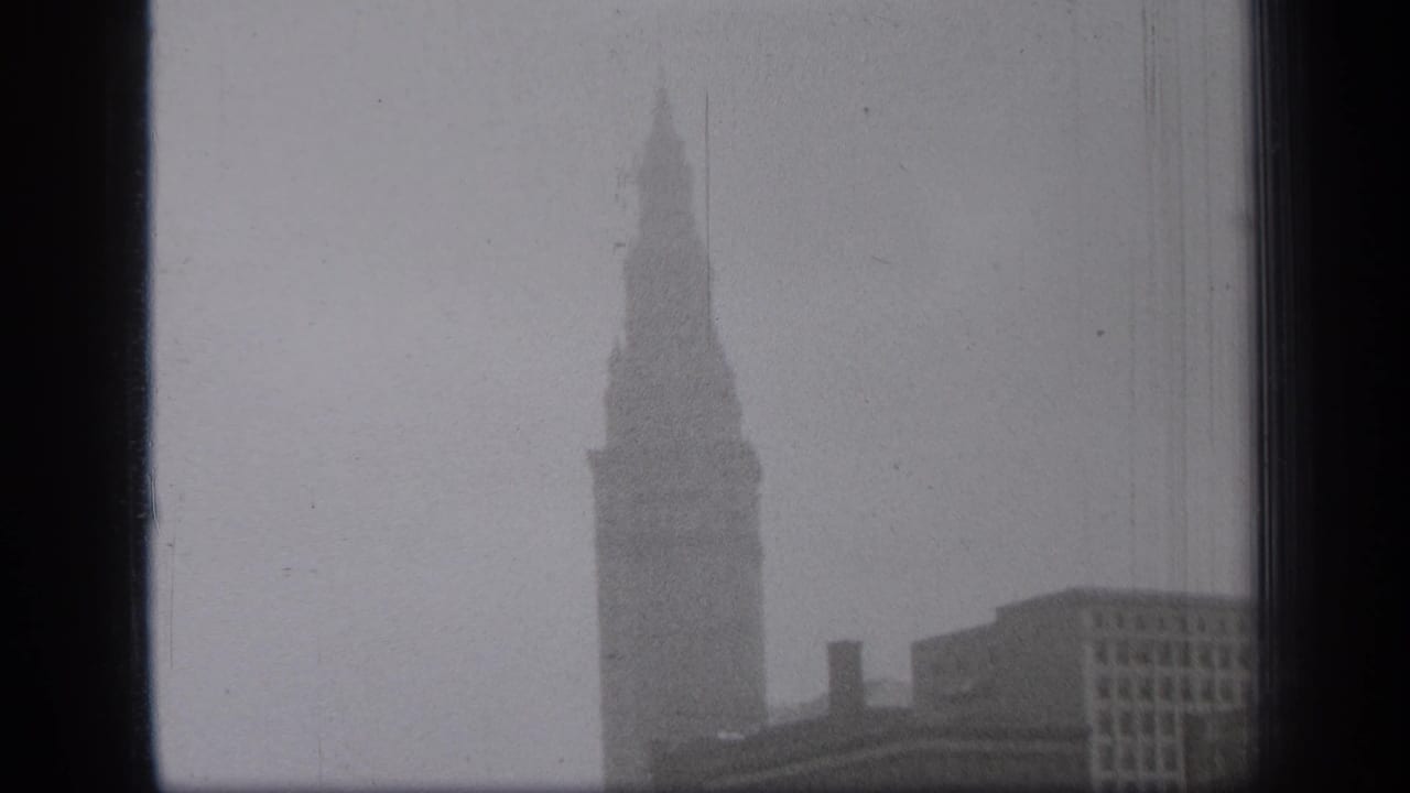 Tall spired building seen through a dark window frame on a hazy day.
