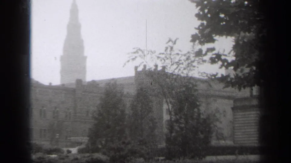 1938 Cleveland exterior view with a hazy steeple, leafy foreground trees, and older institutional buildings.