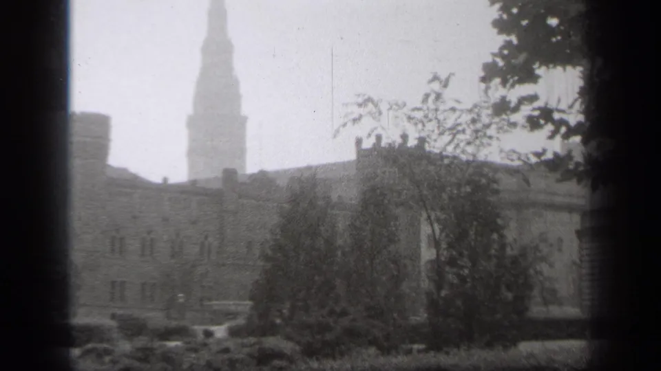 Hazy 1938 Cleveland view of a tall steeple behind landscaped grounds and older stone or brick buildings.
