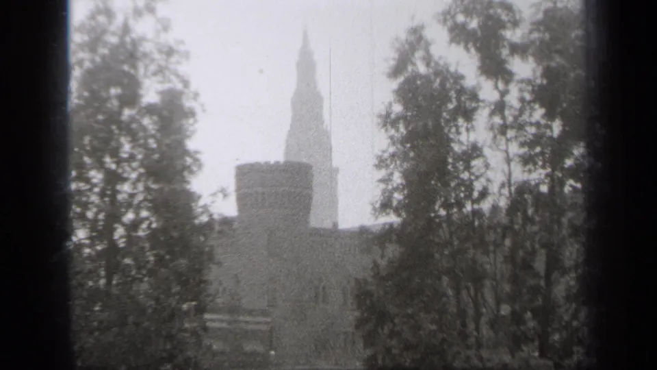 1938 Cleveland 8mm frame showing the stone turret and pointed tower behind tree cover, with the building partly obscured.