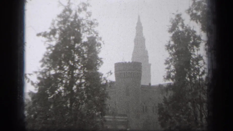 Snowy 1938 Cleveland exterior with a stone building, tower silhouette, and trees viewed from behind a dark window frame.