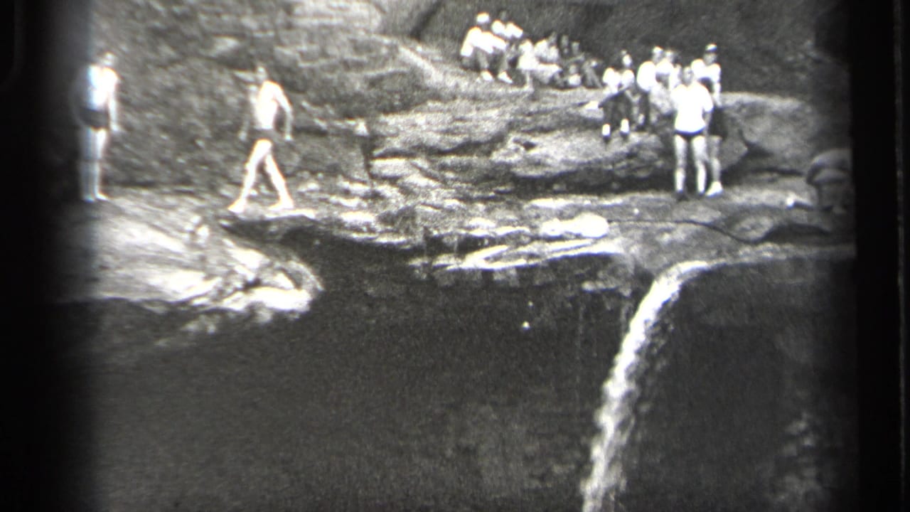 1938 Cleveland-area home-movie frame showing men gathered on rocky ledges above a waterfall and pool.