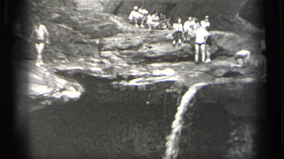 1938 Cleveland, Ohio footage frame with men on a rocky waterfall overlook during a swimming outing.