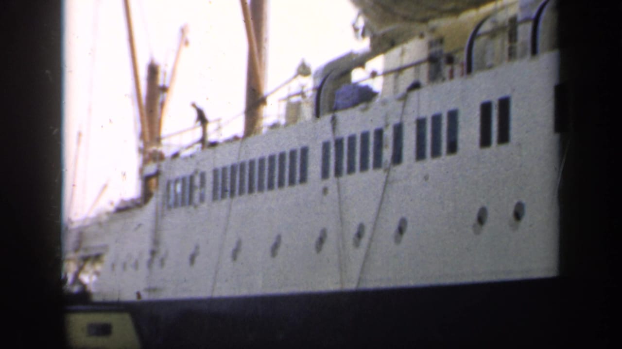 1949 England 8mm frame showing a white docked passenger ship with rectangular windows, portholes, mast rigging, and deck details.