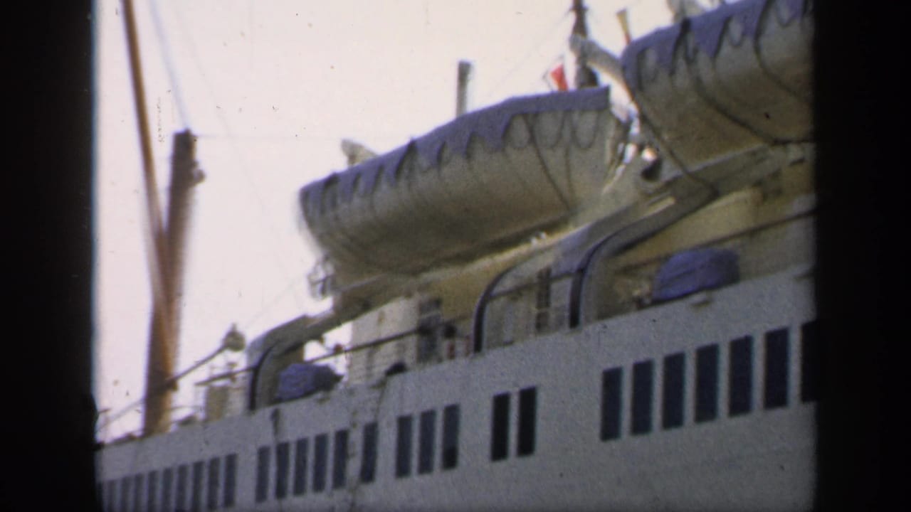 Close dockside view of ship windows with covered lifeboats above the deck.