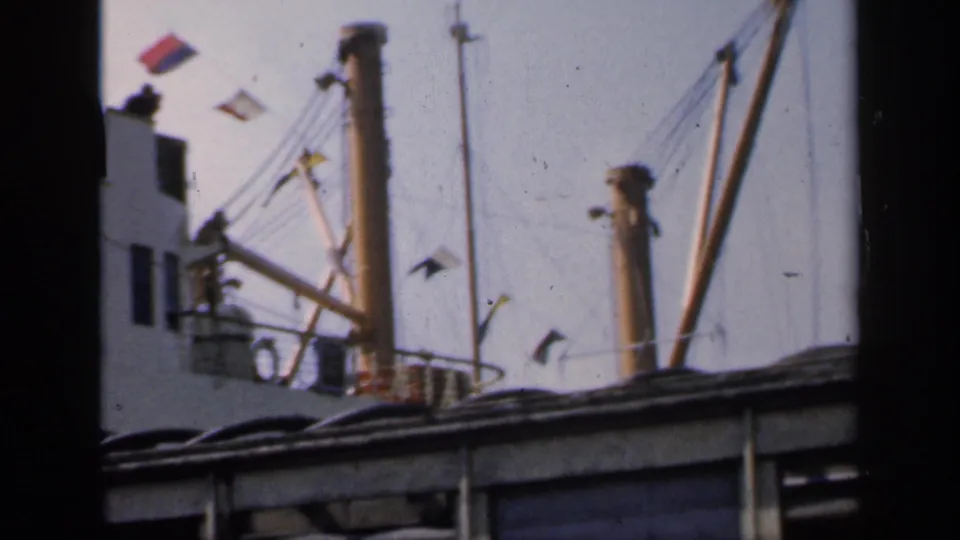 1949 England 8mm frame showing ship rigging, signal flags and deck structures behind a dark foreground obstruction.