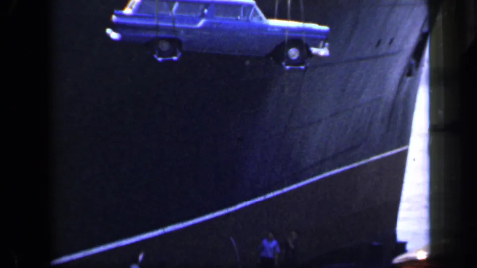 The blue station wagon hangs near the ship's side as tiny dockside figures stand below in the England 1949 port footage.