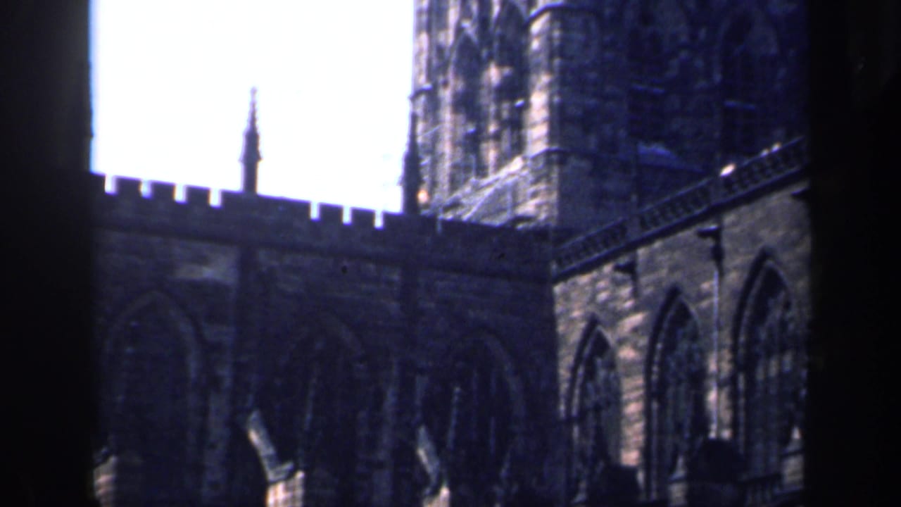Gothic stone church tower and arched windows against a bright sky.