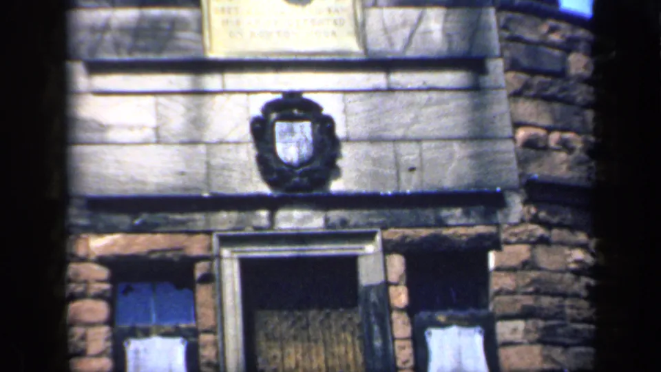 The upward tilt reaches a stone plaque and crest above the entrance on the 1949 England masonry building exterior.