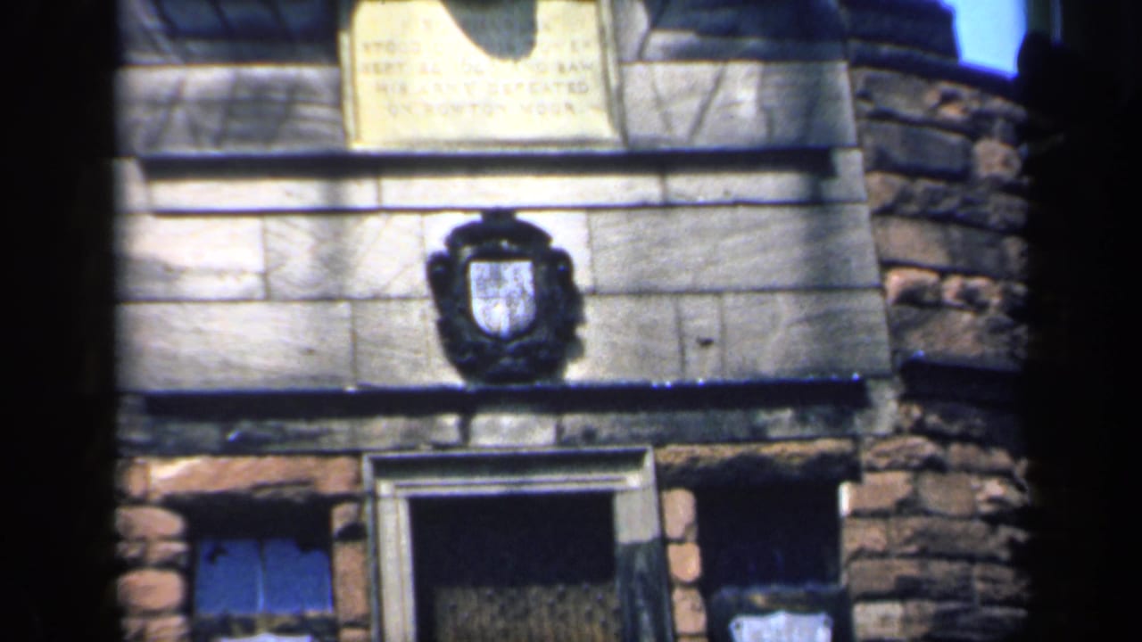 Upper stone facade with plaque, coat of arms, doorway edge, and dark film borders.