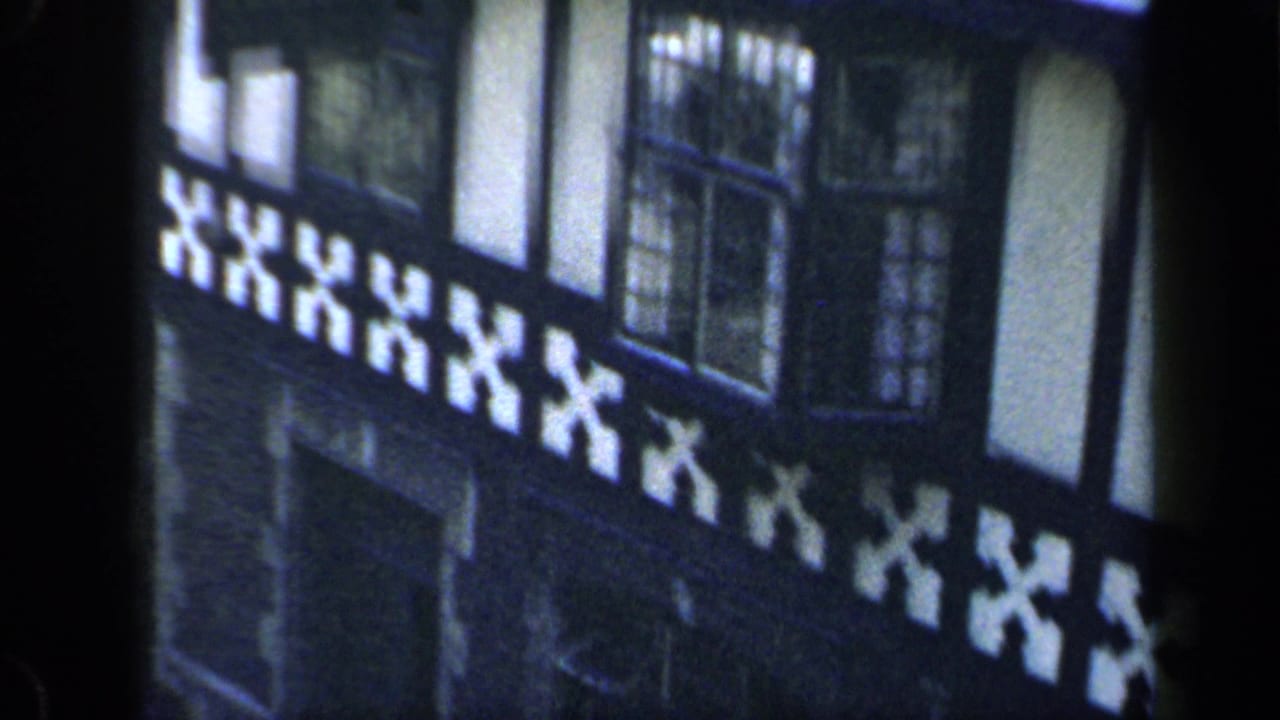 1949 England 8mm frame showing a timber-framed building facade with white infill, dark beams, and leaded windows.