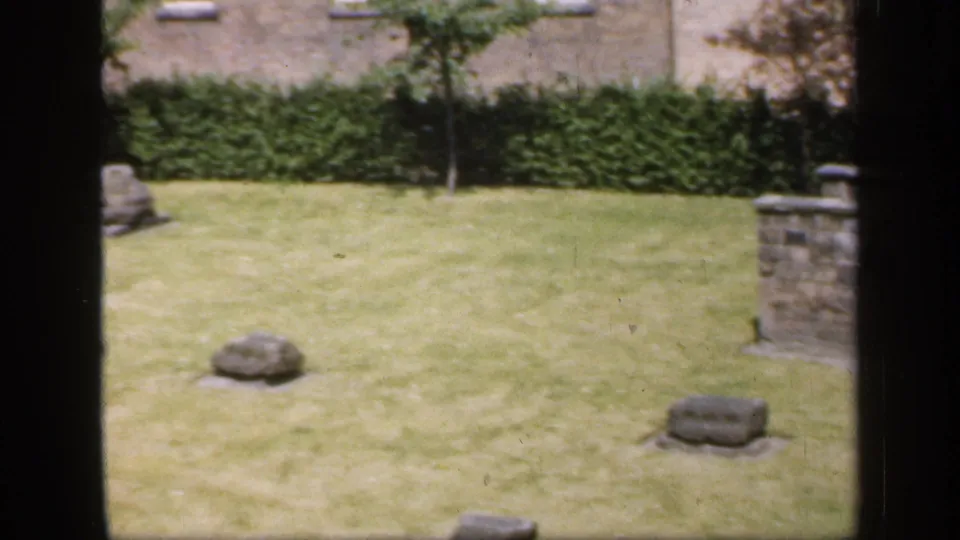 The final 1949 England frame shows the lawn and scattered stone markers with stonework at the right edge.