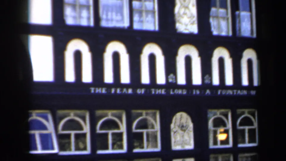 1949 England 8mm frame showing arched windows, decorative trim and the inscription “THE FEAR OF THE LORD IS A FOUNTAIN OF LIFE.”