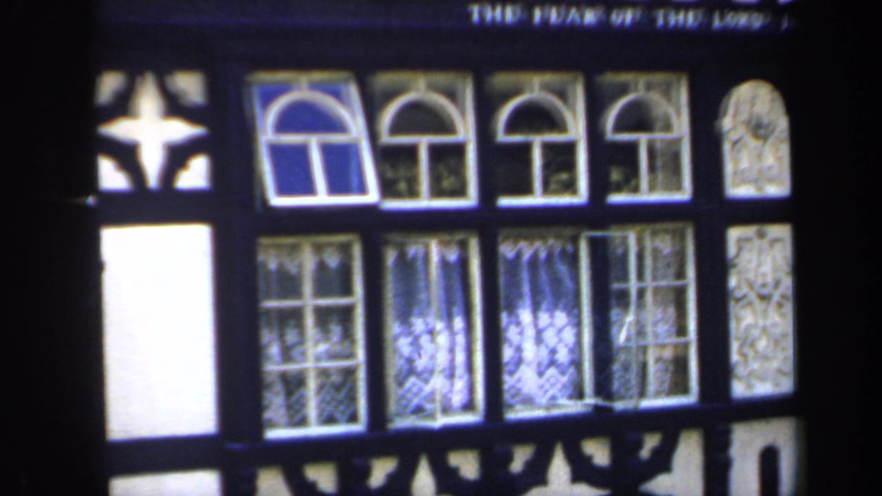 Upper section of the facade with arched windows, patterned glass and partial inscription.