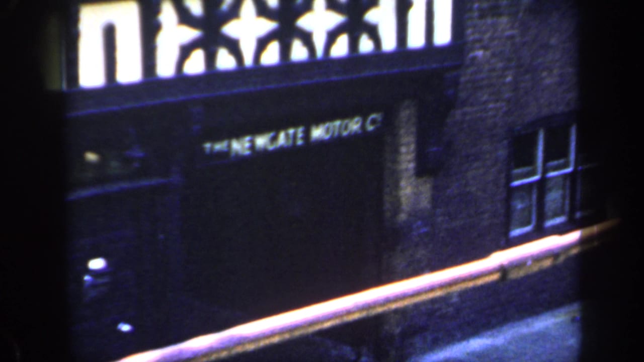 Brick frontage and dark sign area seen through a divided, shadowed frame.