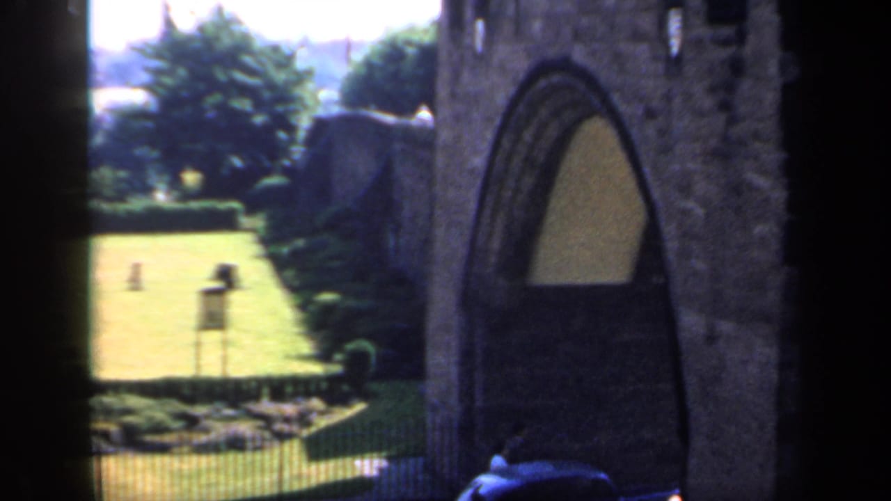 Stone arched doorway beside a bright lawn and garden.