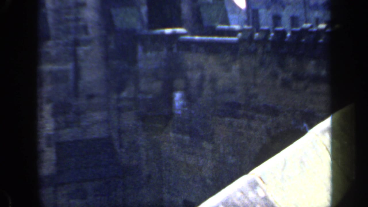 1949 England frame showing a castle parapet and walkway, with dark 8mm frame borders and soft blue-tinted exposure.