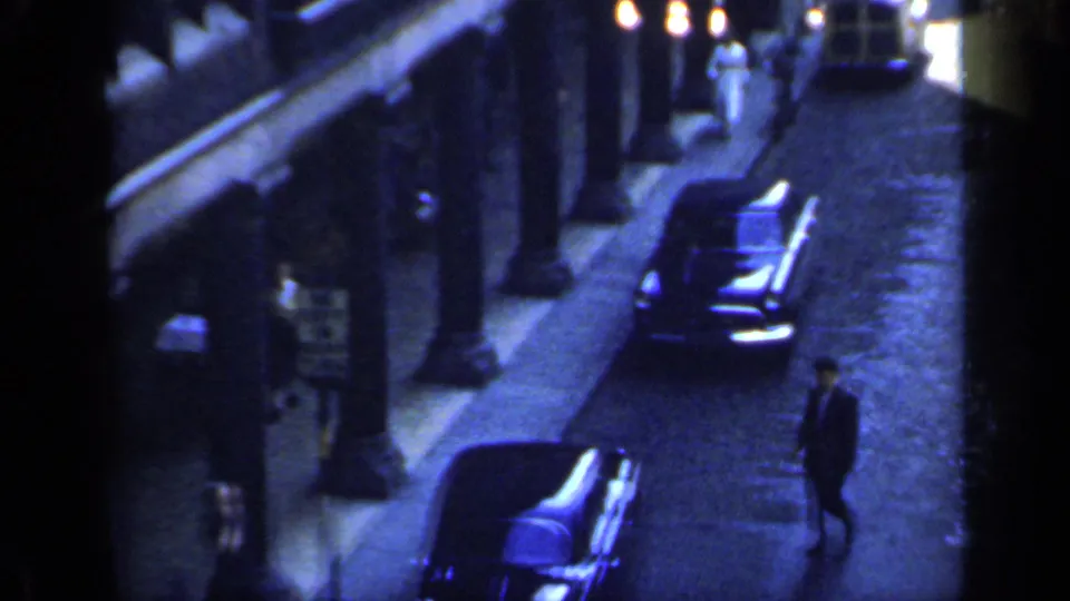 A darker 1949 England street view shows a long black car, a pedestrian, shopfront edges, and lamps along the sidewalk.
