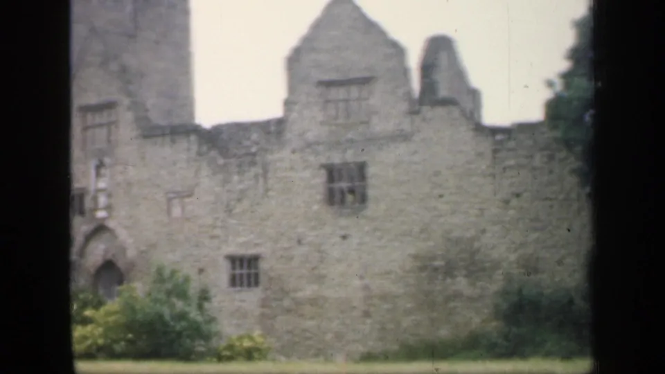 1949 England 8mm frame showing a closer visitor view of stone ruins with an arched doorway and small windows.