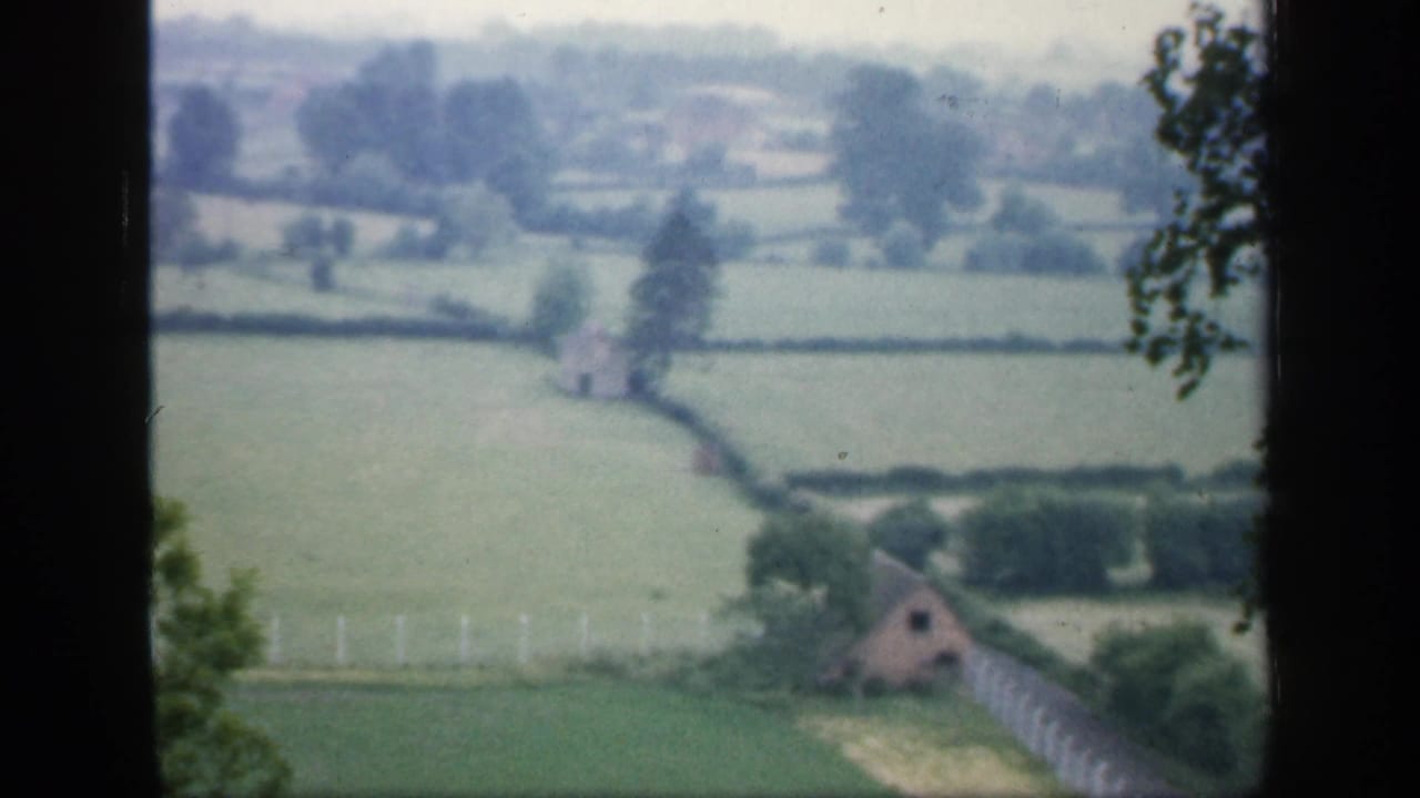 Fields and hedgerows with a small rural building near the lower right edge.