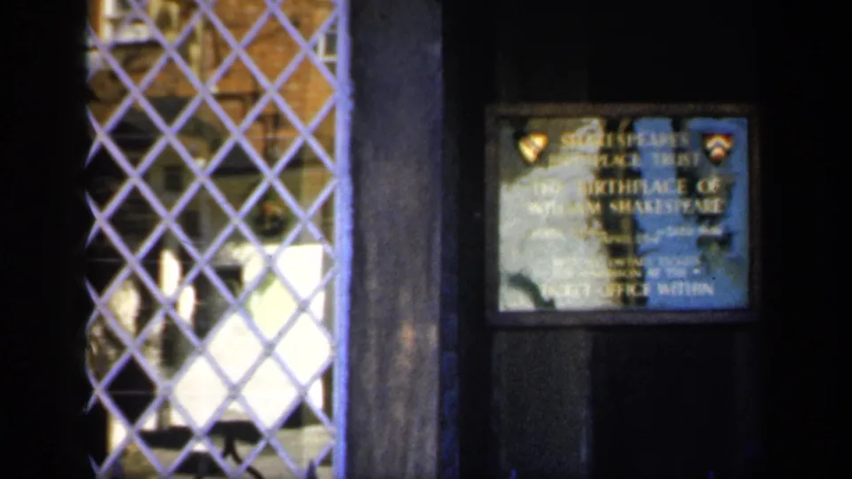 1949 England frame showing a Shakespeare Birthplace plaque on dark wood beside a diamond-patterned window grille.