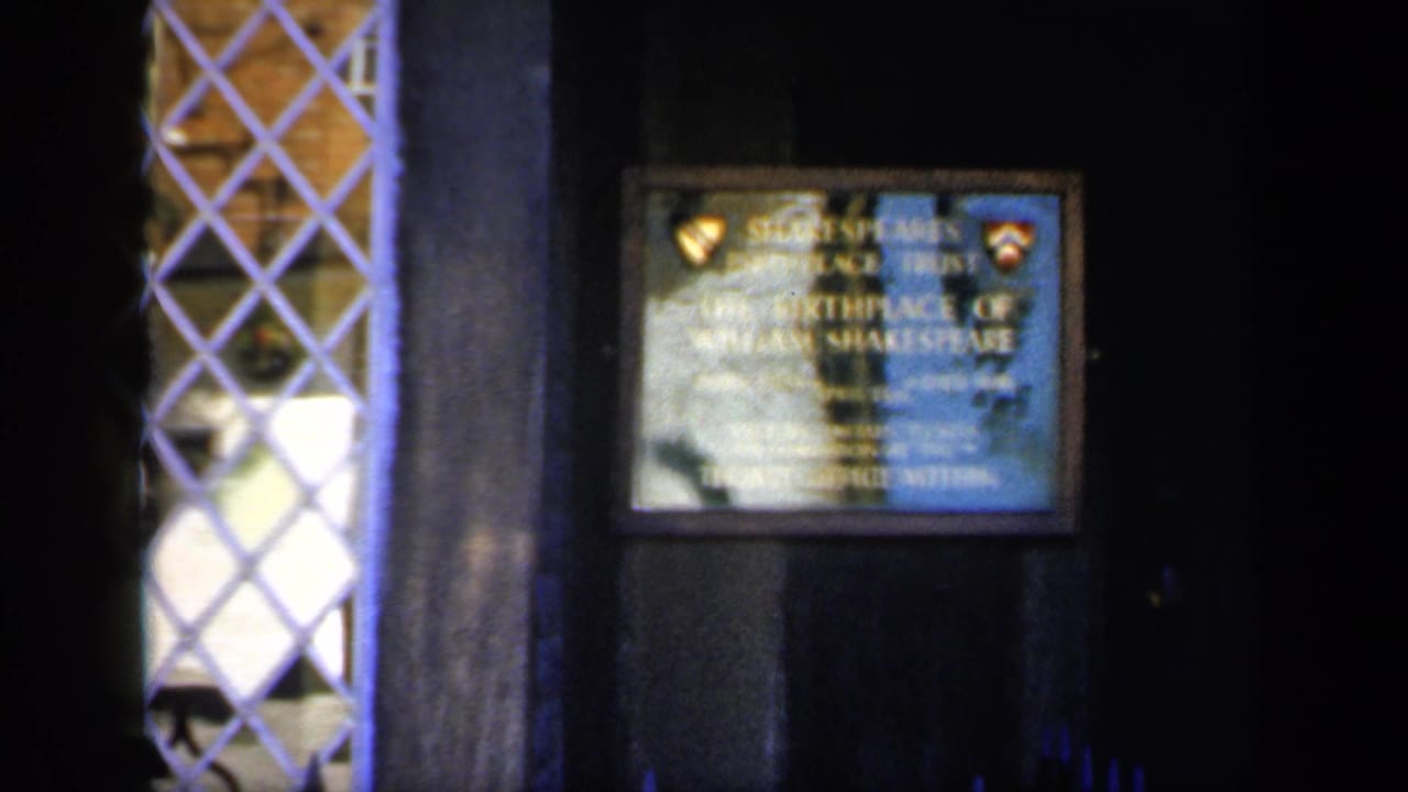 Dark wall with a framed Shakespeare birthplace plaque and a leaded window at left.