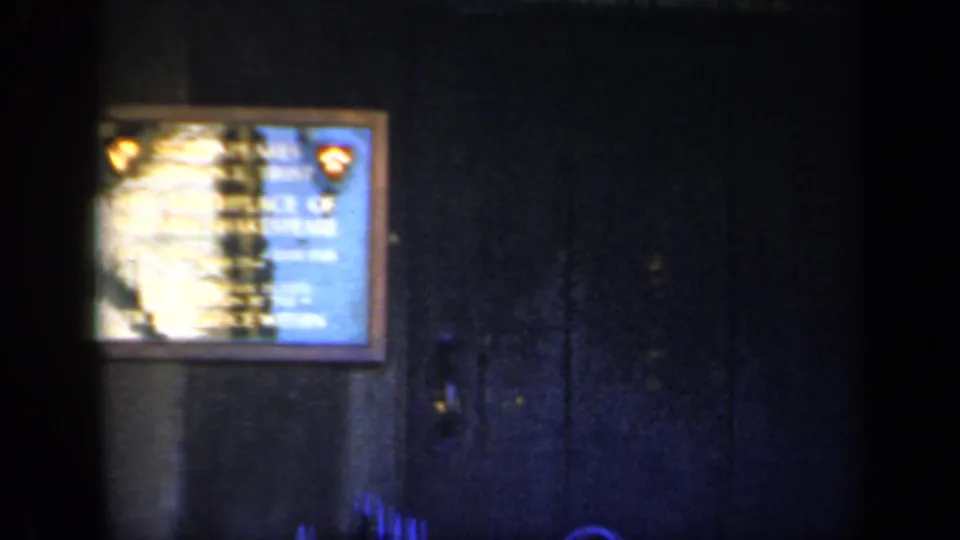 1949 England home-movie frame with a Shakespeare birthplace plaque on a dark exterior wall, softened by blur and uneven exposure.
