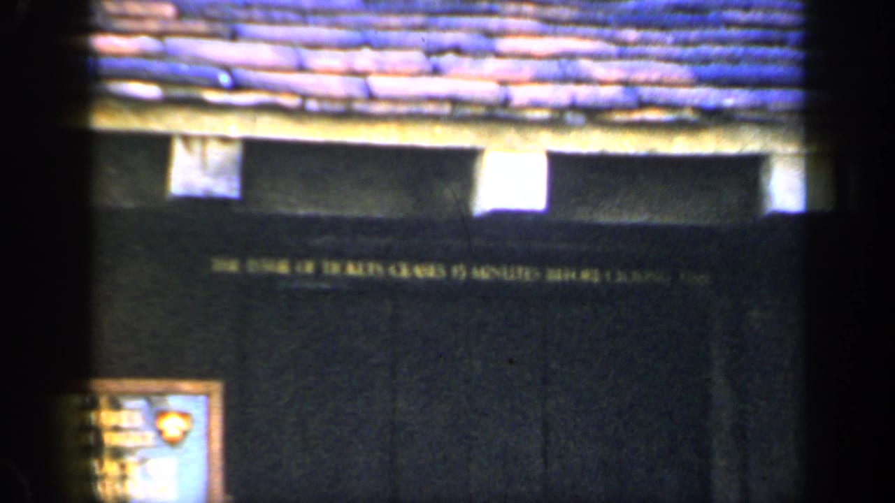 1949 England 8mm frame showing a dark historic building facade, tiled roof and posted ticket-closing notice.