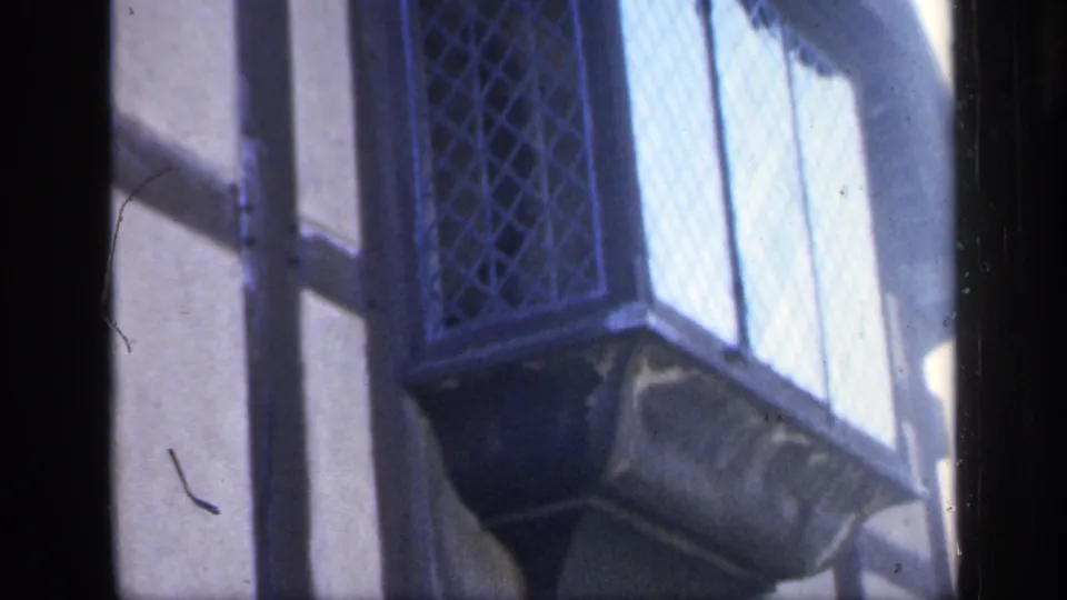 1949 England 8mm frame of a diamond-paned window and projecting exterior detail on the historic building.