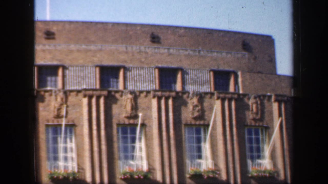 Brick Art Deco-style building seen through a dark window frame.