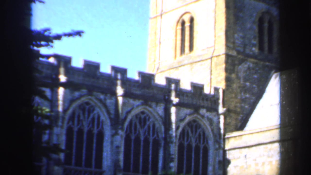 Church tower and arched windows partly framed by dark vertical foreground shadows.