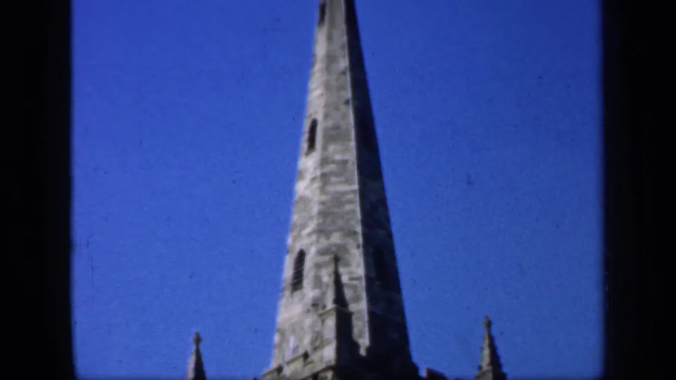 1949 England 8mm frame ending on the high spire and upper church tower with dark film borders visible.