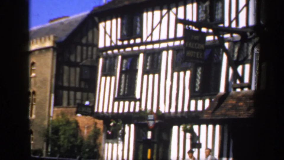 1949 England view of The Falcon Hotel frontage, with pedestrians near the doorway and strong contrast on the facade.