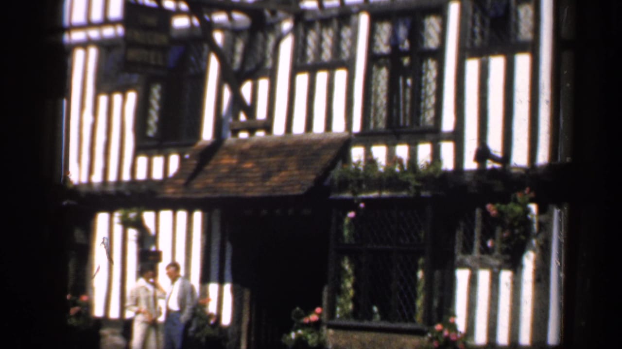 Black-and-white timber-framed building with two adults standing near the entrance.