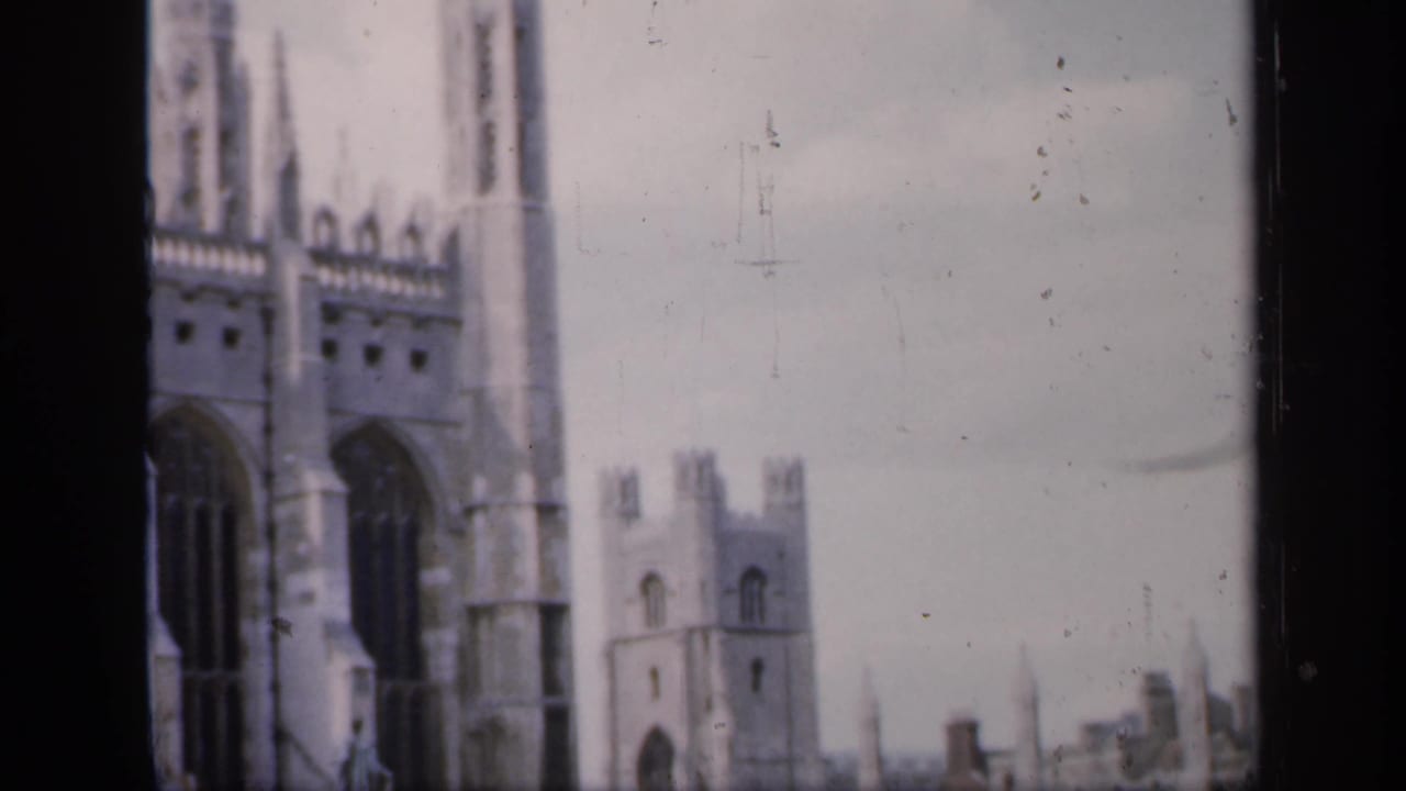 Close view of tall Gothic cathedral windows and spires beside a distant tower.