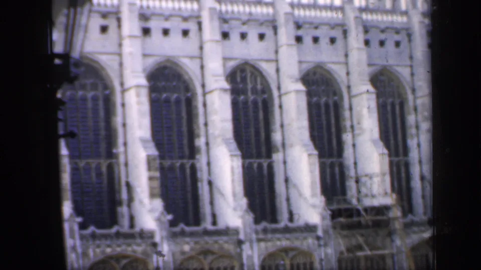 1949 England 8mm view of a Gothic cathedral facade with pointed windows, pale stonework, and visible film-frame edges.