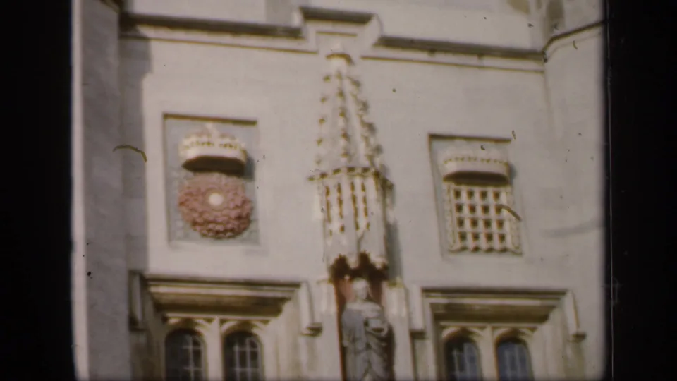 Close 1949 England view of carved stonework, a statue niche, arched windows, and crest-like ornament on a historic building facade.